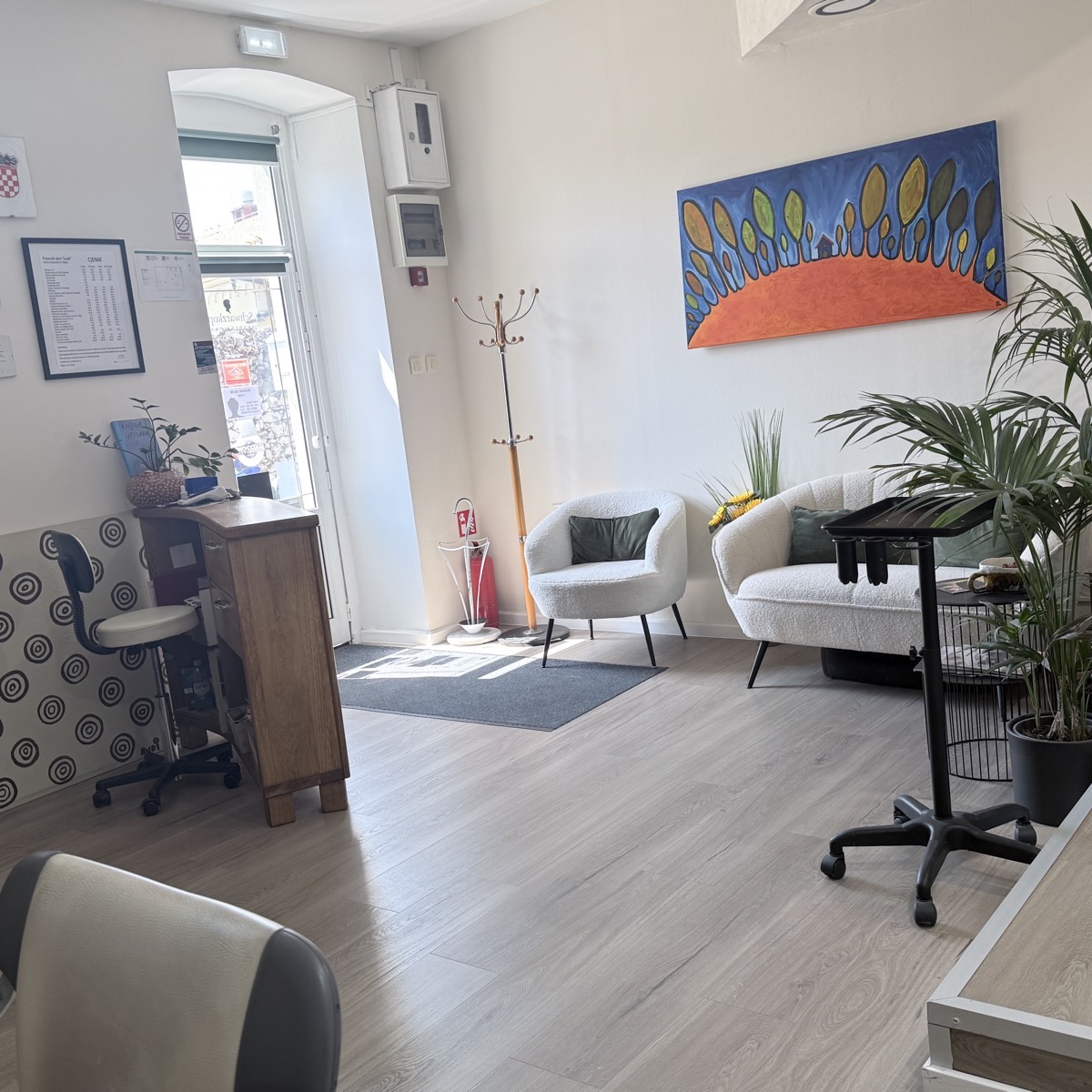 Ulaz u salon sa staklenim vratima, vješalicom i uokvirenim cjenikom na zidu